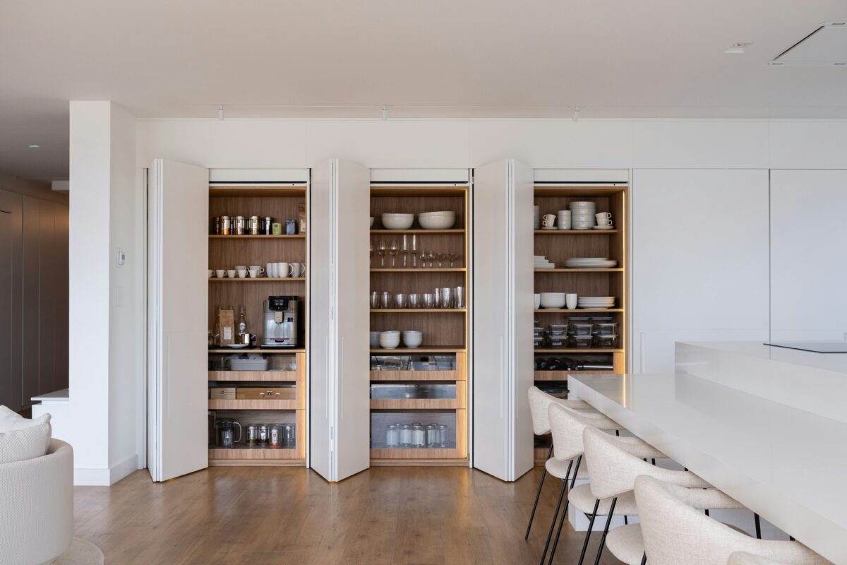 Modern kitchen with open white cabinets and organized wood shelves.