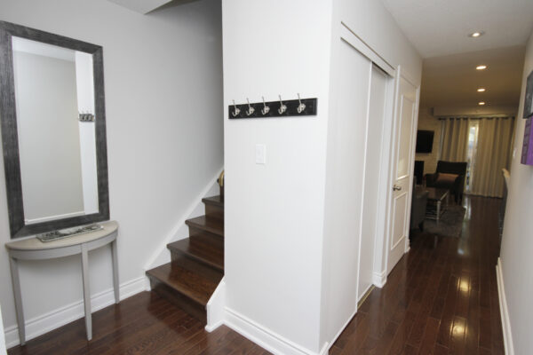 Corridor with mirror and side table and staircase and coat hooks on wall and hallway