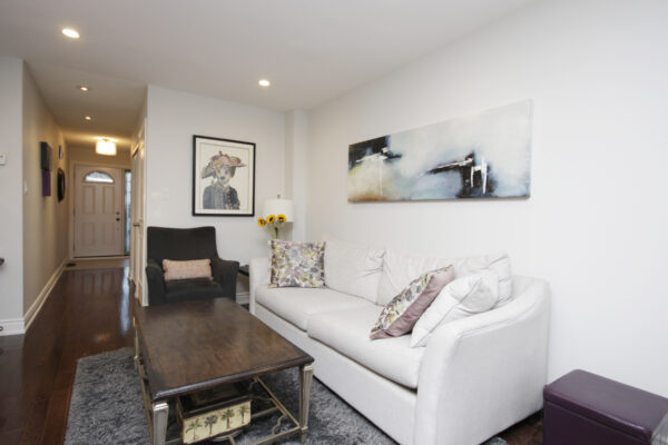 Living room with a white couch and black sofa chair with pillows and paintings on the wall