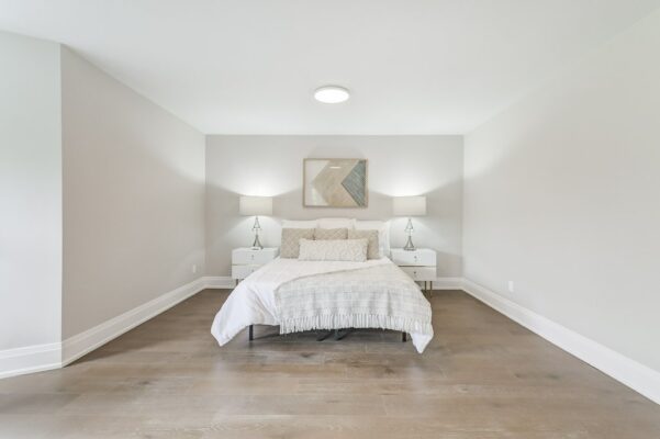 Neutral bedroom with white and beige bedding, matching nightstands, and geometric wall art.