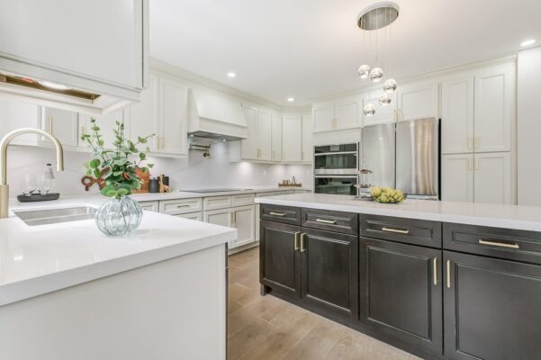 White upper cabinets, dark lower cabinets, large island, and spherical pendant lights.