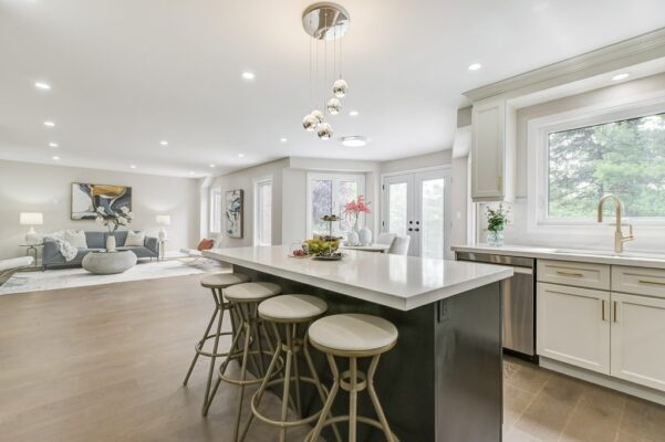 Kitchen with large island and living room with grey sofa and abstract art.