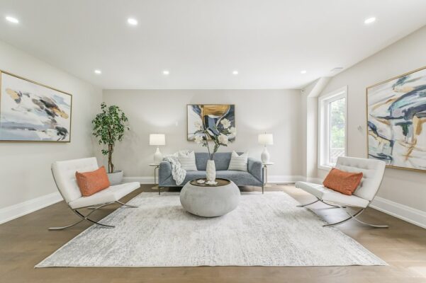 Gray sofa, white lounge chairs, concrete coffee table, and abstract wall art.