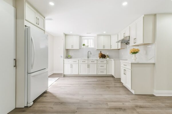 White cabinetry, stainless sink, marble backsplash, and decorative accents.