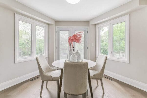 Round white dining table with beige chairs and red foliage centrepiece.