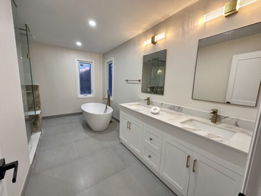 Bathroom with freestanding tub, double vanity, marble counters, and glass shower.