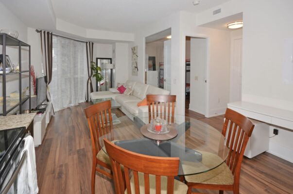 Open living and dining space with glass table, white sectional, and media console.