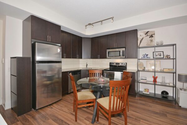 Small contemporary kitchen with dark wood cabinets, stainless appliances, and round dining table.