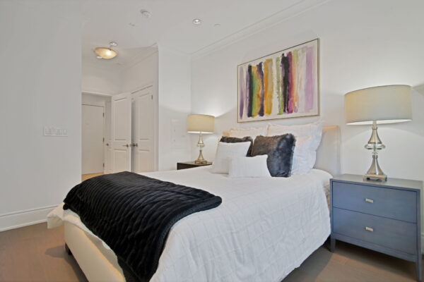 Contemporary bedroom with side tables and lamps on top and a abstract painting above