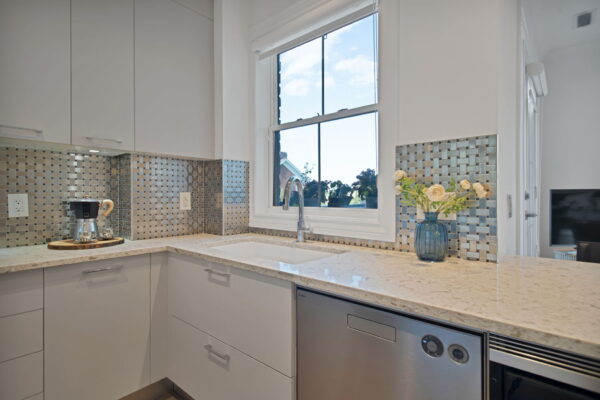 Kitchen window and stainless steel tap and sink and flowers on counter