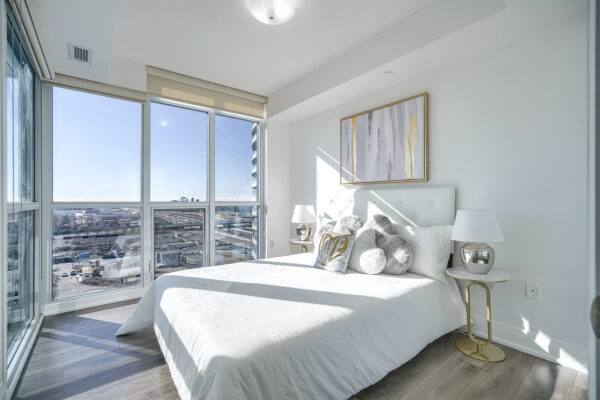 Modern bedroom with bed, side-tables, and lamps on each with a modern painting above