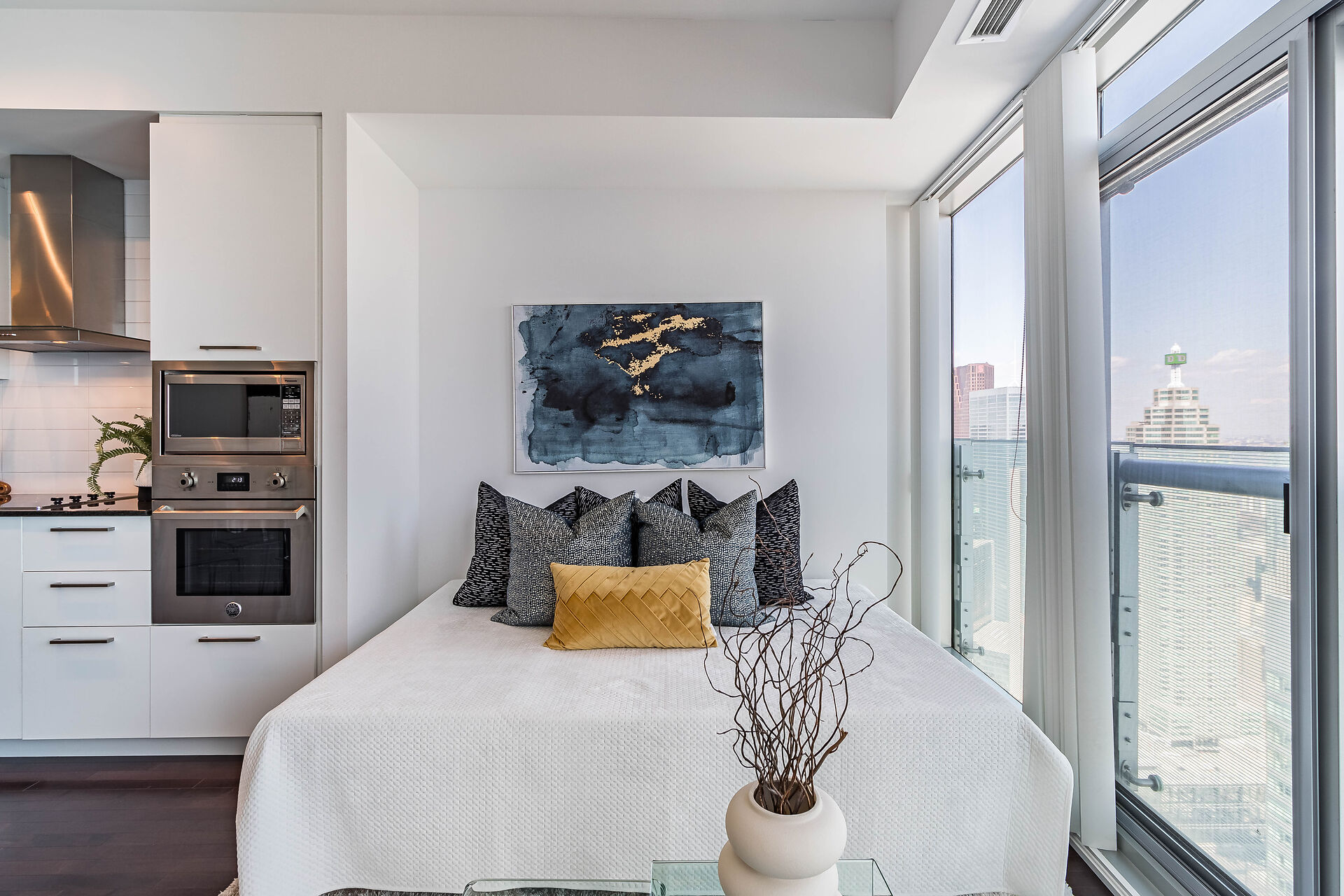 Bed and kitchen studio with painting and plant on a coffee table