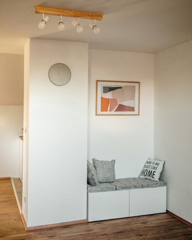 Cozy corner seating nook with built-in bench, patterned cushions, and wall art.