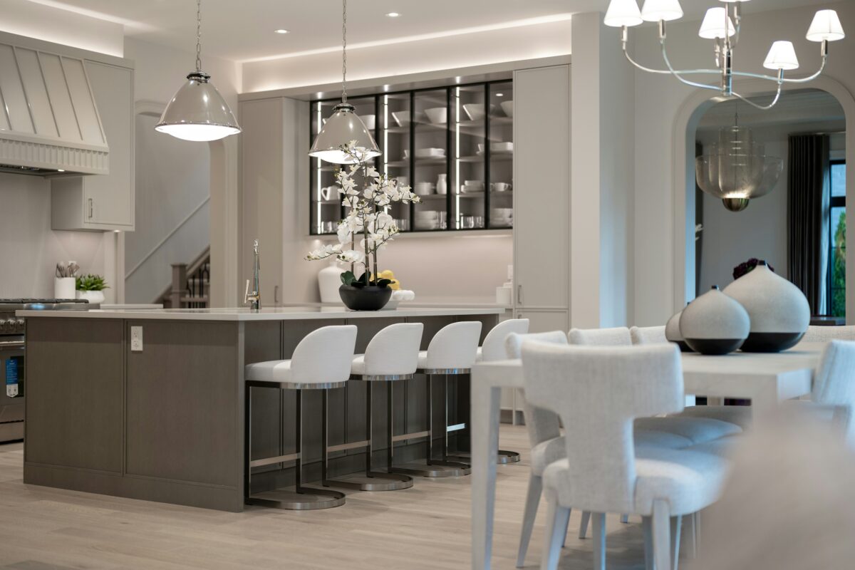 Open-concept grey kitchen with large island, pendant lights, and modern dining area.