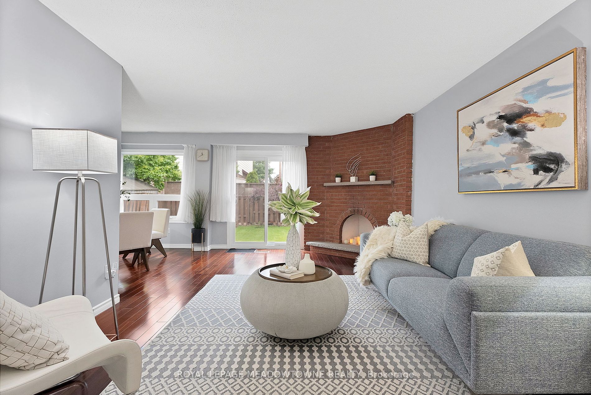 Mid-century living room staged with a blue sofa and round coffee table and brick fireplace