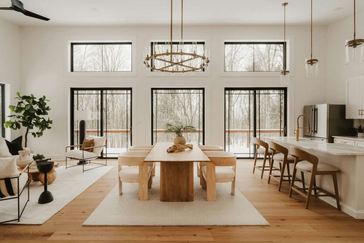 Open-concept living and dining room with large windows and forest views.