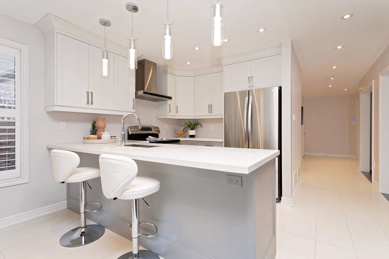 Small corner modern white kitchen staged with stainless steel appliances
